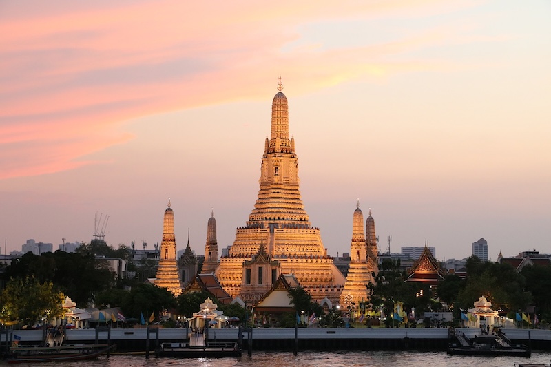Vue du Wat Arun à Bangkok illuminé au crépuscule depuis la rivière Chao Phraya