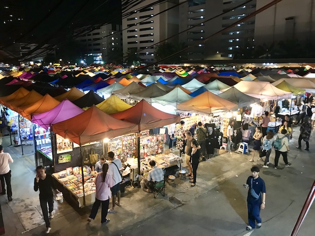 Vue d’un marché de nuit à Bangkok avec des tentes multicolores et des visiteurs en promenade