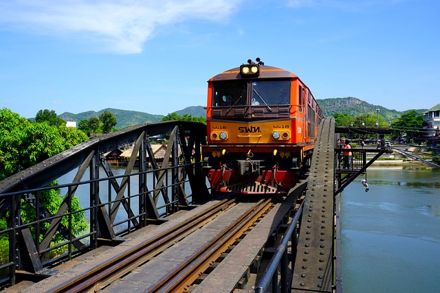 Train orange franchissant l'historique pont au-dessus de la rivière, en Thaïlande