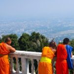 Jeunes moines en habits orange observant Chiang Mai depuis les hauteurs du Doi Suthep