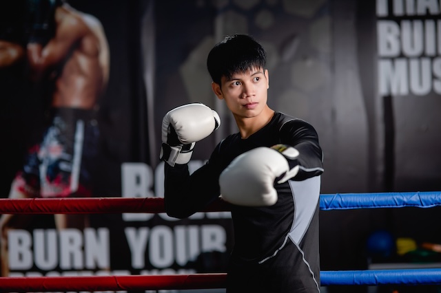 Un boxeur de cette discipline concentré, en garde, sur un ring, prêt à combattre.