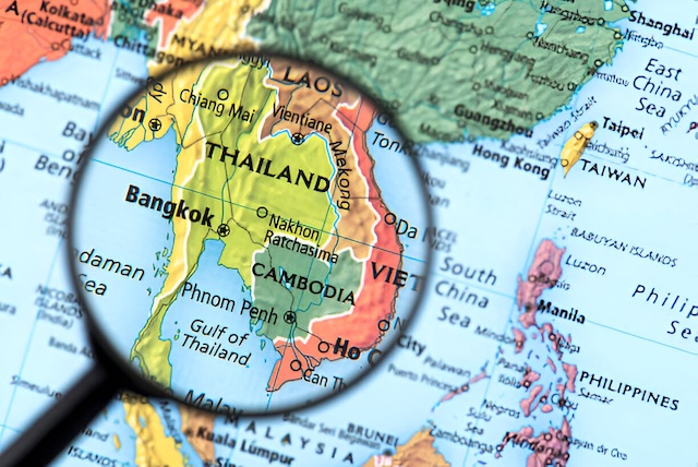 Carte de la Thaïlande vue à travers une loupe, mettant en valeur Bangkok, Chiang Mai et les principales régions touristiques du pays