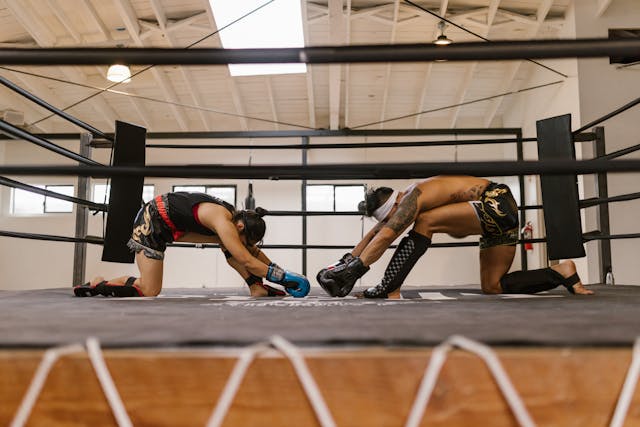 Deux pratiquants de discipline du Siam, un homme et une femme, s'étirant avec discipline sur un ring avant un entraînement.