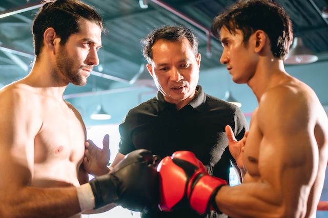 Deux boxeurs de boxe thaïlandaise se fixant droit dans les yeux, poing contre poing, avant le début du combat sur le ring.