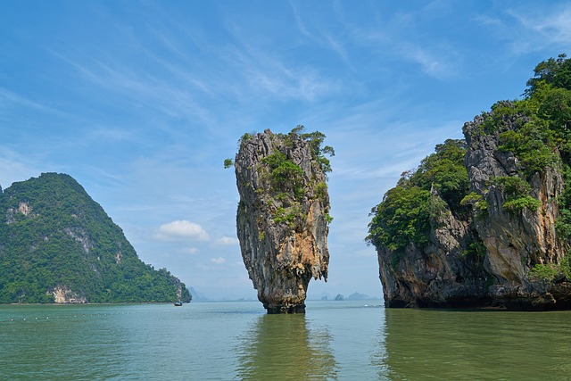 Le rocher de Koh Tapu, surnommé James Bond Island, émergeant des eaux vertes de la baie de Phang Nga, avec d'autres falaises karstiques en arrière-plan.