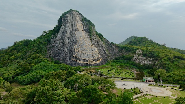 Gravure dorée géante de Bouddha sur la falaise de Khao Chi Chan entourée de verdure en Thaïlande