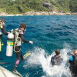 Groupe de plongeurs sous-marins équipés en train de sauter d'un bateau de plongée pour explorer les fonds marins au large des côtes thaïlandaises.
