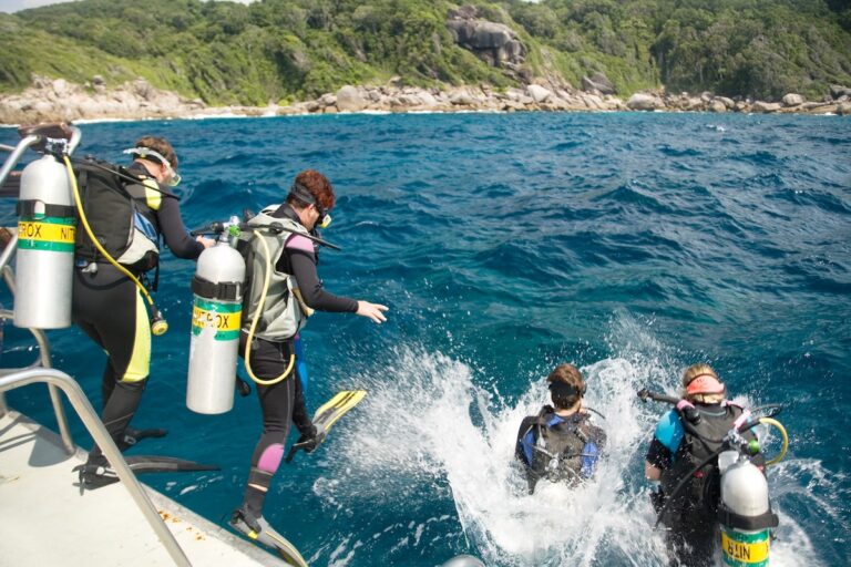 Groupe de plongeurs sous-marins équipés en train de sauter d'un bateau de plongée pour explorer les fonds marins au large des côtes thaïlandaises.
