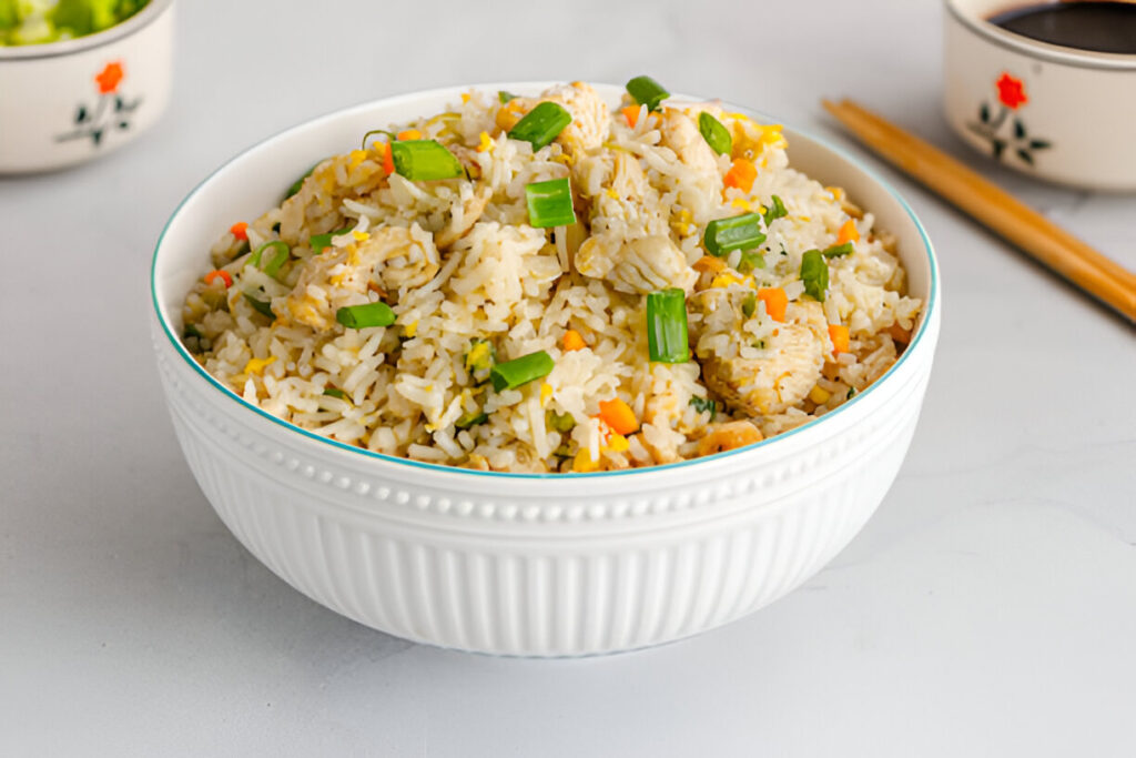 Bol de riz frit thaïlandais au poulet, carottes, œufs brouillés et oignons verts