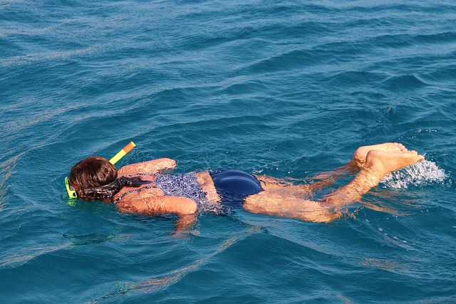 Une personne équipée d'un masque et d'un tuba flotte à la surface de l'eau bleue claire de la mer d'Andaman, pratiquant le snorkeling.