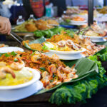 Stand de street food en Thaïlande avec nouilles sautées, crevettes et calamars servis sur feuilles de bananier