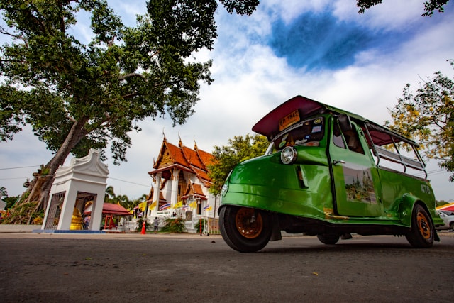 Tuk-tuk vert de style tête de grenouille garé devant un temple thaïlandais dans le parc historique d'Ayutthaya.