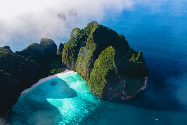 Vue aérienne de la plage de sable blanc de Maya Bay, nichée dans une crique aux eaux turquoise et entourée d'immenses falaises verdoyantes sur l'île de Koh Phi Phi Leh.