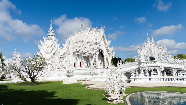 Vue d'ensemble du Wat Rong Khun, le Temple Blanc de Chiang Rai, montrant son architecture blanche immaculée et le pont symbolique menant à l'entrée principale.