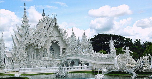 Temple blanc Wat Rong Khun à Chiang Rai avec ses sculptures et son reflet dans l’eau