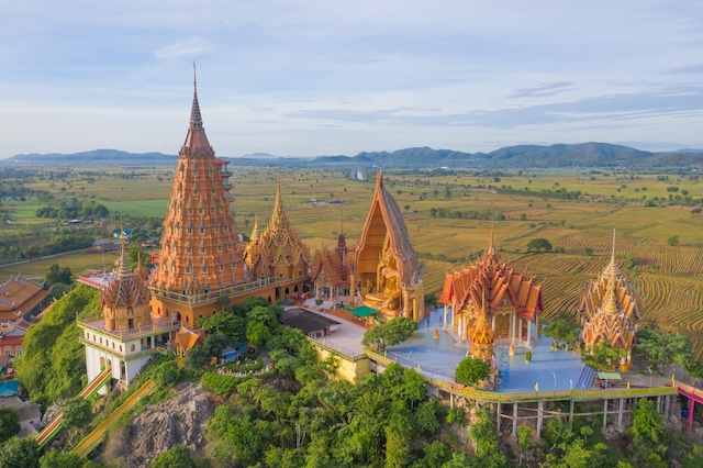 Vue aérienne du Wat Tham Sua (Temple de la Grotte du Tigre) à Kanchanaburi, entouré de rizières, un site culturel majeur en Thaïlande