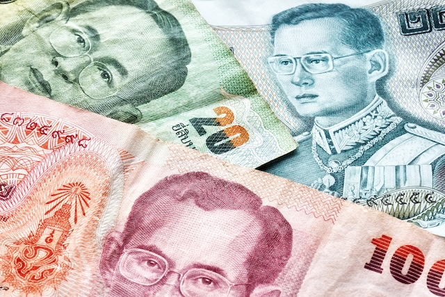 Gros plan sur des billets de Baht thaïlandais de différentes couleurs, illustrant la monnaie locale et la gestion du budget pour un voyage en Thaïlande.