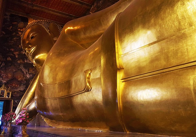 Vue en contre-plongée de l'imposante statue dorée du Bouddha couché au Wat Pho, montrant sa taille monumentale et son expression sereine.