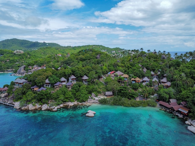 Vue aérienne de bungalows de luxe nichés sur une colline verdoyante surplombant une baie aux eaux turquoise et claires à Koh Tao.