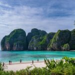 Vue de la célèbre plage de Maya Bay à Koh Phi Phi, avec son sable blanc, son eau turquoise et ses imposantes falaises karstiques verdoyantes.