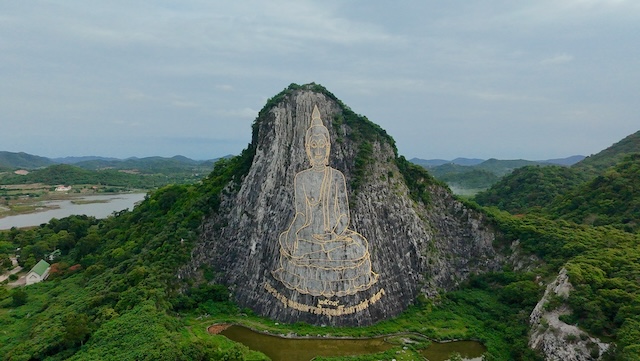 Vue aérienne de la Montagne de Bouddha à Khao Chi Chan, montrant l'immense image de Bouddha gravée à l'or sur la falaise et entourée d'un paysage verdoyant.