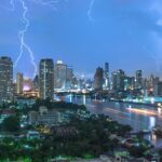 Vue panoramique de la skyline de Bangkok la nuit pendant un violent orage, avec de multiples éclairs illuminant le ciel au-dessus du fleuve Chao Phraya.