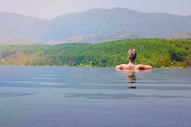 Une femme se relaxant dans une piscine à débordement avec vue sur les montagnes verdoyantes, illustrant le type de séjour possible avec un budget confort ou luxe en Thaïlande.