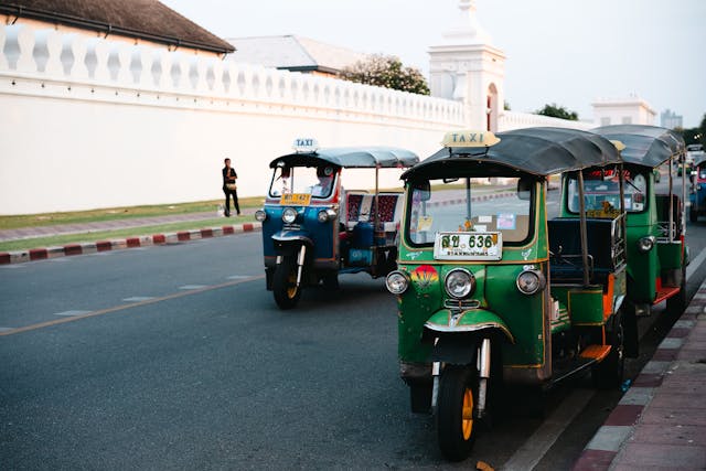 Des tuk-tuks emblématiques de Bangkok garés dans la rue, illustrant un poste de dépense du budget transport en Thaïlande.