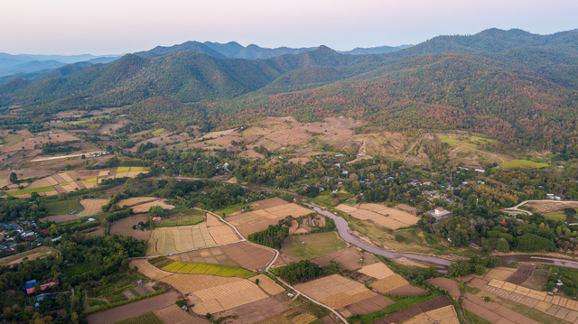 Vue aérienne de la vallée de Pai, avec la rivière et un patchwork de rizières, entourée par les montagnes verdoyantes de Thaïlande.