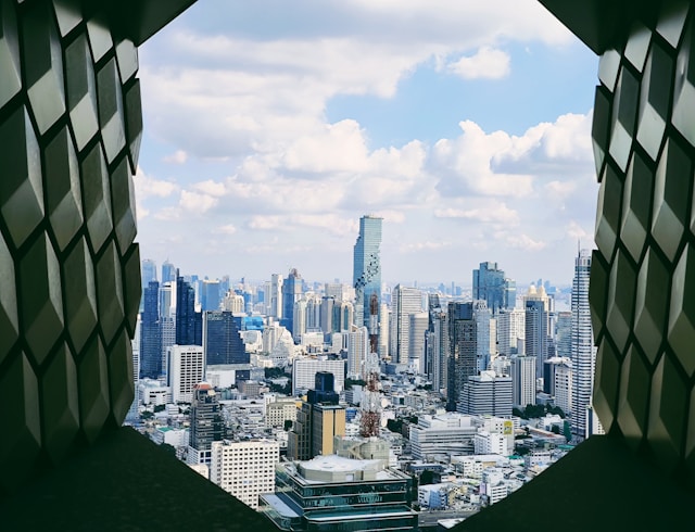 Vue sur les gratte-ciels de Bangkok, dont la tour MahaNakhon, encadrée par la fenêtre géométrique d'un appartement, illustrant le logement et le coût de la vie pour un expatrié.