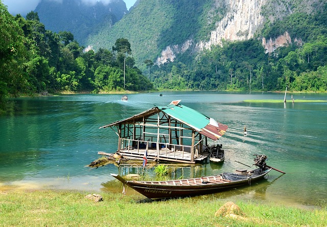 Un bateau long-tail amarré près d'un bungalow flottant sur les eaux émeraude du lac Cheow Lan, un exemple d'écotourisme dans le parc de Khao Sok.