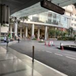 Entrée principale et voies d'accès du Bumrungrad International Hospital, un grand complexe hospitalier moderne à Bangkok avec des drapeaux internationaux.