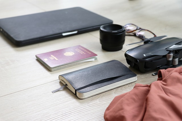 Le matériel d'un digital nomad posé sur une table : passeport, ordinateur portable, drone, et carnet de notes.