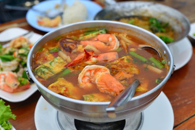 Marmite de Gaeng Som, un curry acide thaïlandais, remplie de grosses crevettes et de morceaux d'omelette.