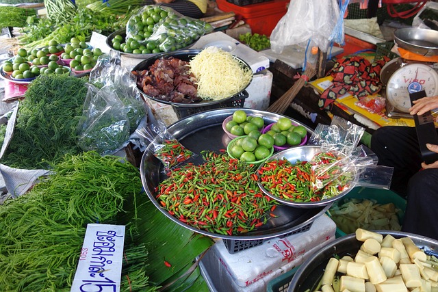 Un étal coloré sur un marché en Thaïlande, avec des piments, des citrons verts et des herbes fraîches, illustrant la gastronomie locale et l'écotourisme.