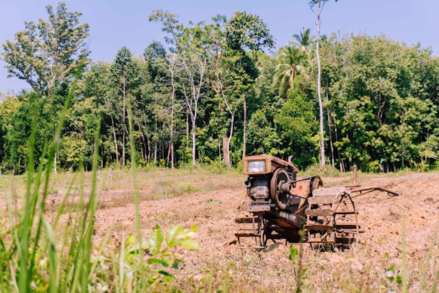 Un motoculteur rouge prêt à labourer une rizière à Koh Yao Noi, avec une forêt tropicale luxuriante en arrière-plan.