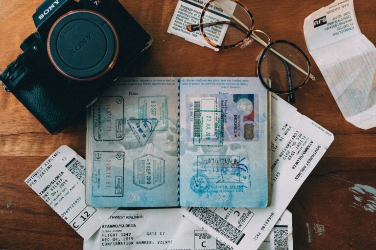 Passeport ouvert rempli de tampons de visas, posé à côté de cartes d'embarquement et d'un appareil photo, illustrant la préparation d'un voyage en Asie du Sud-Est.