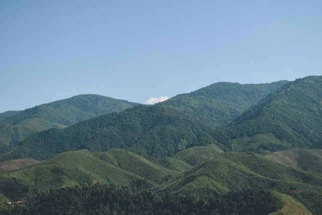 Vue panoramique des montagnes verdoyantes de Nan en Thaïlande, s'étendant à perte de vue sous un ciel clair.