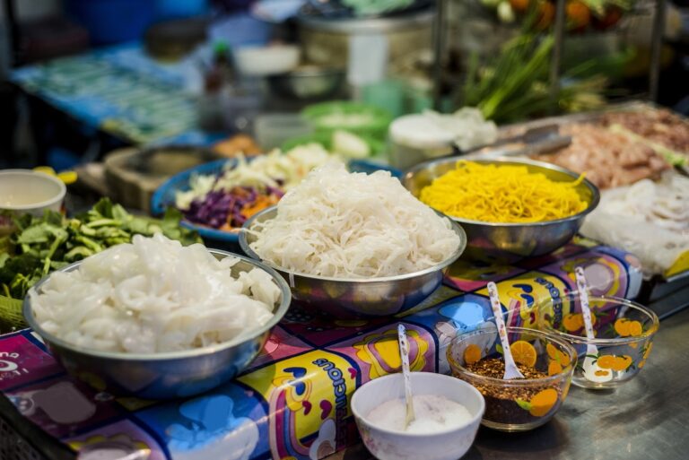 Stand de street food en Thaïlande avec des bols de nouilles et d'ingrédients frais pour la préparation de plats.