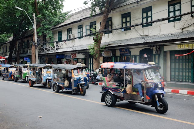 Une file d'attente de tuk-tuks colorés dans une rue de Bangkok, un moyen de transport iconique en Thaïlande.