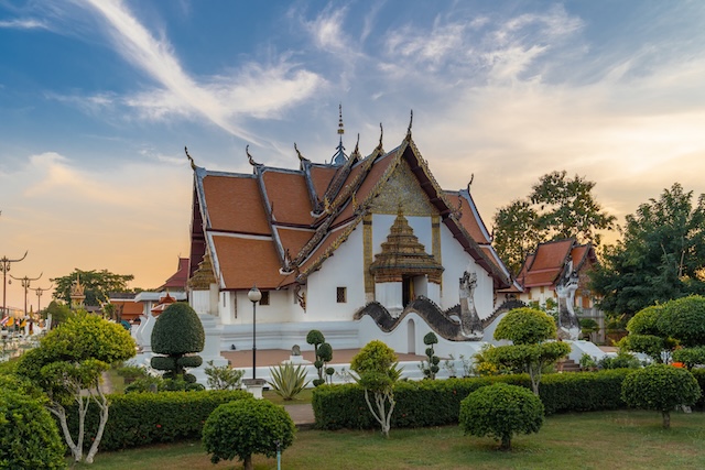 Vue extérieure du temple Wat Phumin à Nan en Thaïlande, avec son architecture Lanna et ses jardins au coucher du soleil.