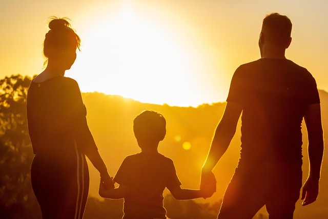 Silhouette d'une famille, deux adultes et un enfant, se tenant la main lors d'un coucher de soleil doré en Thaïlande