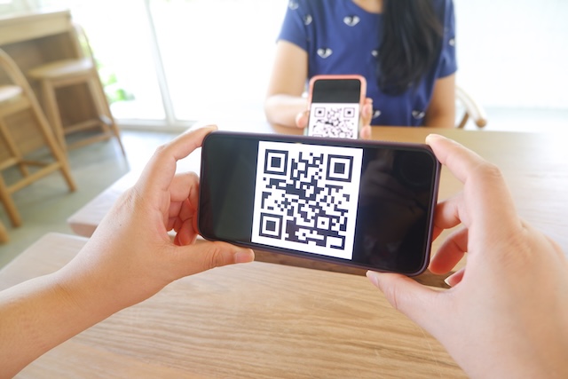 Une personne paie dans un commerce en Thaïlande en scannant un QR Code avec son smartphone, une alternative pratique à la carte bancaire pour les détenteurs de visa DTV.