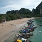 Vue sur la plage de Railay à Krabi, destination nature avec ses falaises calcaires et ses bateaux traditionnels, alternative à Phuket.