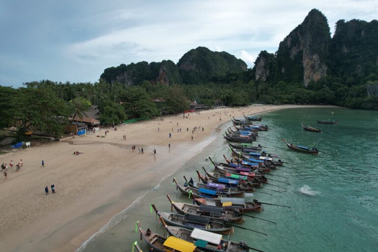 Vue sur la plage de Railay à Krabi, destination nature avec ses falaises calcaires et ses bateaux traditionnels, alternative à Phuket.