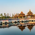 Pavillons d'un temple bouddhiste en Thaïlande se reflétant dans l'eau, illustrant les préceptes fondamentaux du bouddhisme.