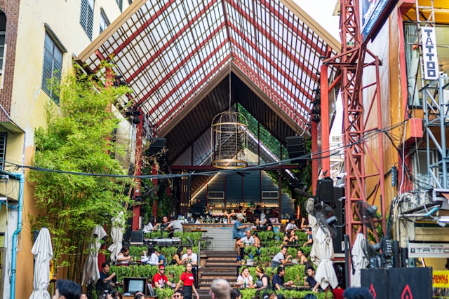Vue d'un bar moderne sur plusieurs niveaux avec une terrasse animée de jeunes, illustrant la vie nocturne de Khao San Road.