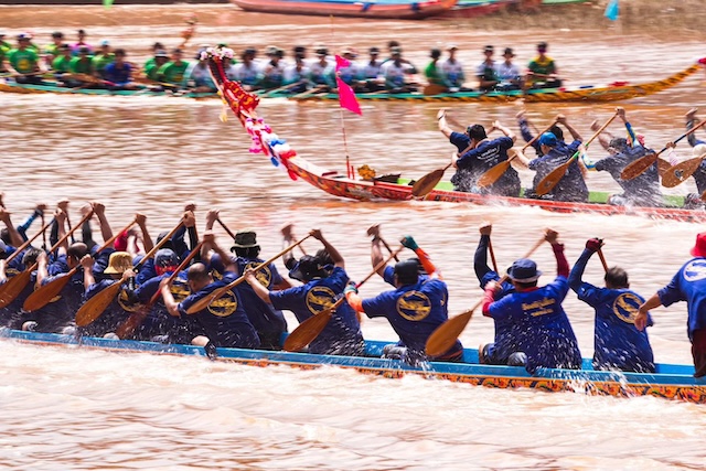 Deux équipes de rameurs en uniforme pagayant en parfaite synchronisation sur de longues pirogues décorées lors du festival de courses de bateaux de Nan, en Thaïlande.