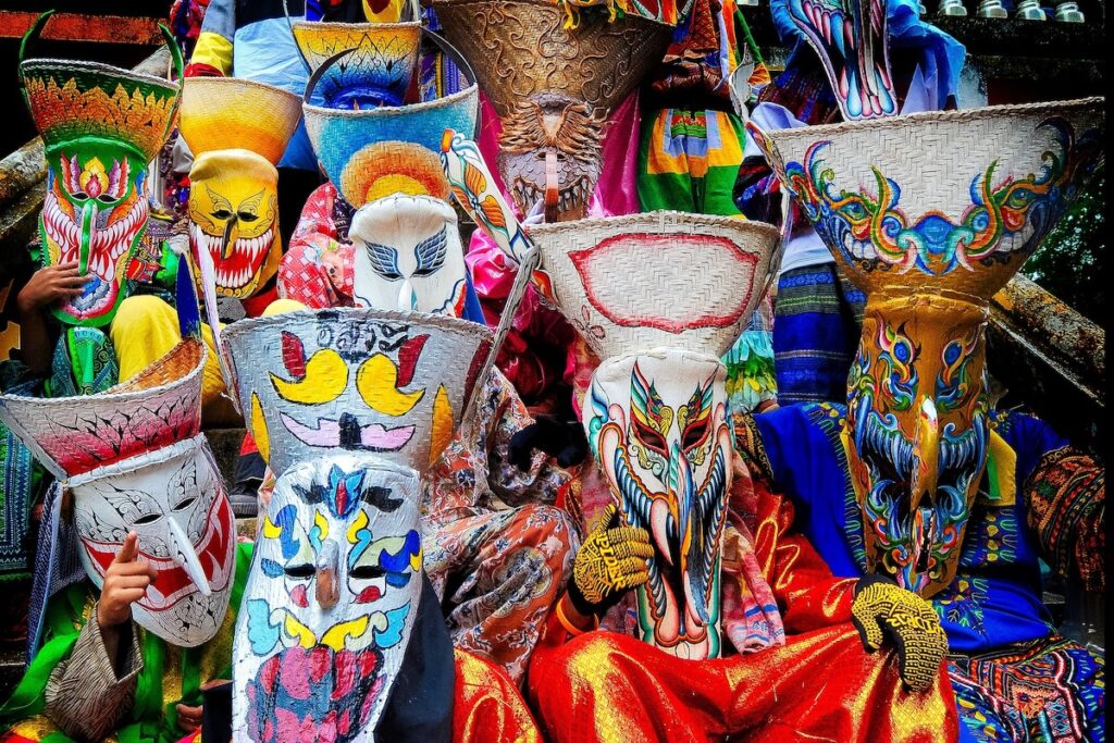 Plusieurs masques traditionnels du festival Phi Ta Khon, très colorés et aux formes variées, portés par des participants lors d'un des festivals les plus insolites de Thaïlande.