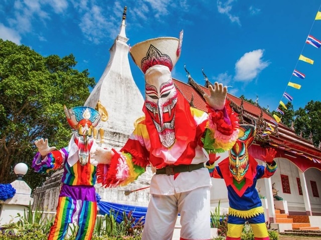 Personnes en costumes traditionnels colorés dansant lors du festival Phi Ta Khon, un des festivals insolites de Thaïlande